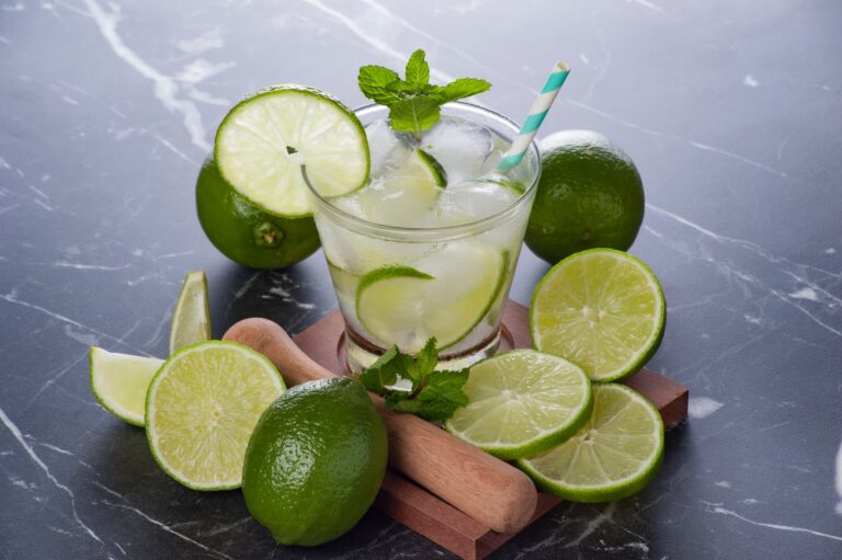 Glass of Caipirinha, with green lemons around it